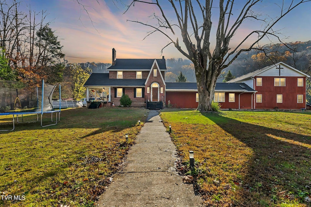 view of front of house featuring a mountain view, a trampoline, and a yard