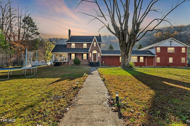 106 W Sycamore Ave, Big Stone Gap, VA 24219 - traditional-style home featuring a trampoline, a front lawn, brick siding, and a chimney