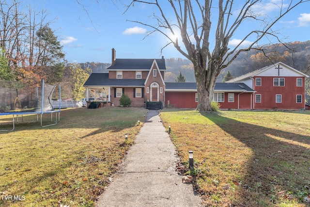 view of front of house featuring a mountain view, a front lawn, and a trampoline