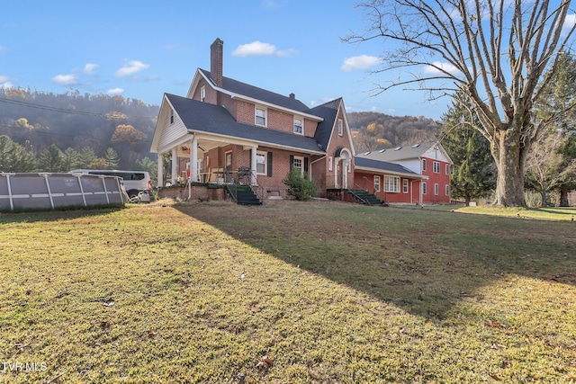 106 W Sycamore Ave, Big Stone Gap, VA 24219 - rear view of property featuring a porch, a chimney, brick siding, a lawn, and an outdoor pool