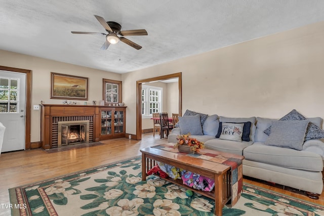 106 W Sycamore Ave, Big Stone Gap, VA 24219 - living area with wood finished floors, ceiling fan, a brick fireplace, a textured ceiling, and baseboards