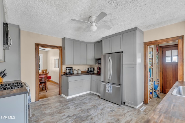 106 W Sycamore Ave, Big Stone Gap, VA 24219 - kitchen with appliances with stainless steel finishes, gray cabinets, a ceiling fan, a textured ceiling, and baseboards