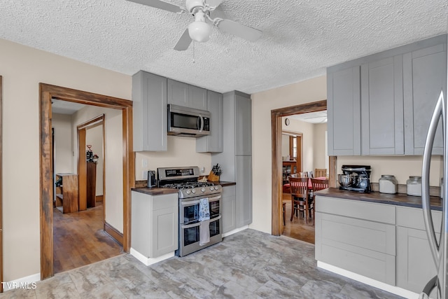 106 W Sycamore Ave, Big Stone Gap, VA 24219 - kitchen with appliances with stainless steel finishes, dark countertops, gray cabinetry, ceiling fan, and baseboards
