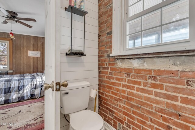 106 W Sycamore Ave, Big Stone Gap, VA 24219 - ensuite bathroom featuring toilet, a ceiling fan, wood walls, and brick wall