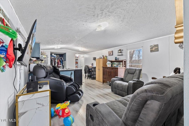 living room featuring a textured ceiling, light hardwood / wood-style flooring, and vaulted ceiling