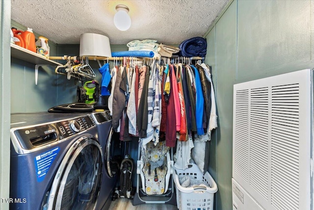 laundry area featuring wood-type flooring, a textured ceiling, and washing machine and clothes dryer