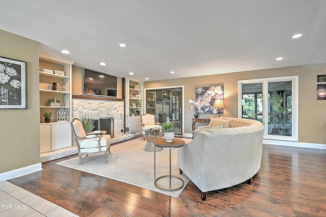 living room featuring hardwood / wood-style flooring, built in features, and a fireplace