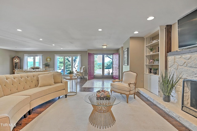 living room featuring a stone fireplace, wood-type flooring, and french doors