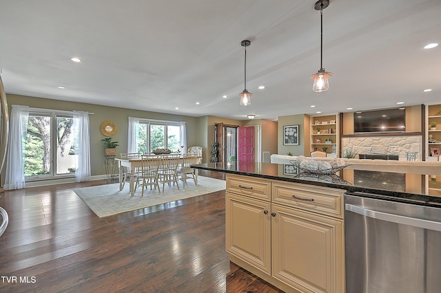 kitchen with stainless steel dishwasher, pendant lighting, cream cabinetry, a fireplace, and dark hardwood / wood-style floors