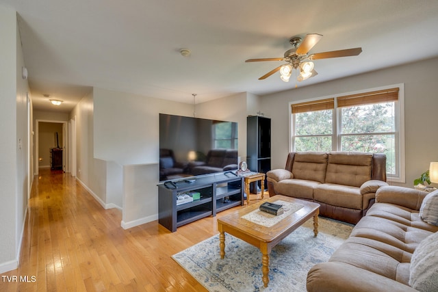 living room with baseboards, a ceiling fan, and light wood-style floors