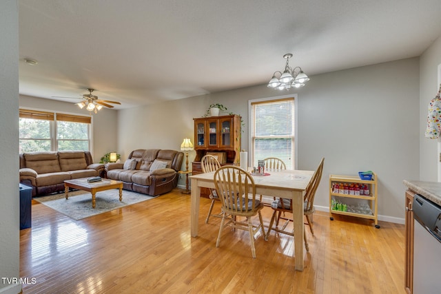 dining room featuring light wood finished floors, baseboards, and ceiling fan with notable chandelier