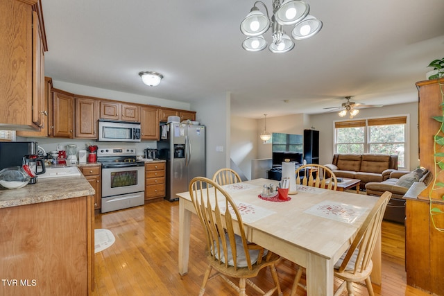 kitchen with light wood finished floors, light countertops, appliances with stainless steel finishes, brown cabinetry, and open floor plan