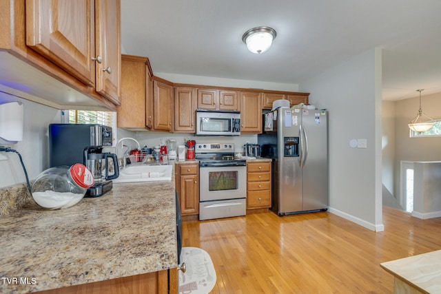 kitchen featuring stainless steel appliances, hanging light fixtures, a sink, and a wealth of natural light