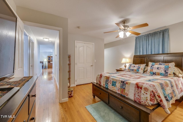 bedroom with light wood-style floors, baseboards, and a ceiling fan