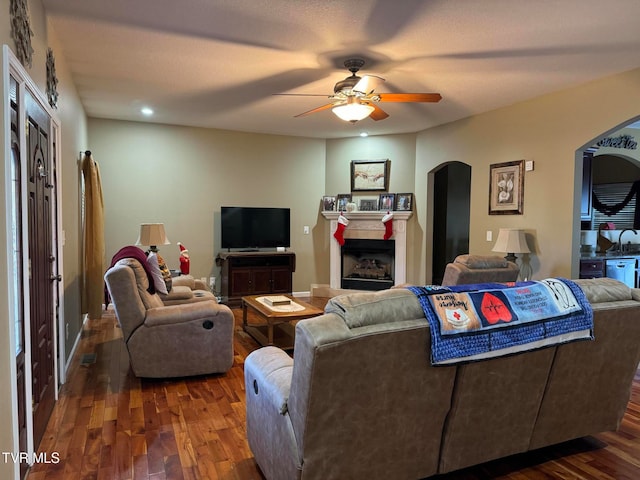 living room with dark hardwood / wood-style floors, ceiling fan, and a textured ceiling