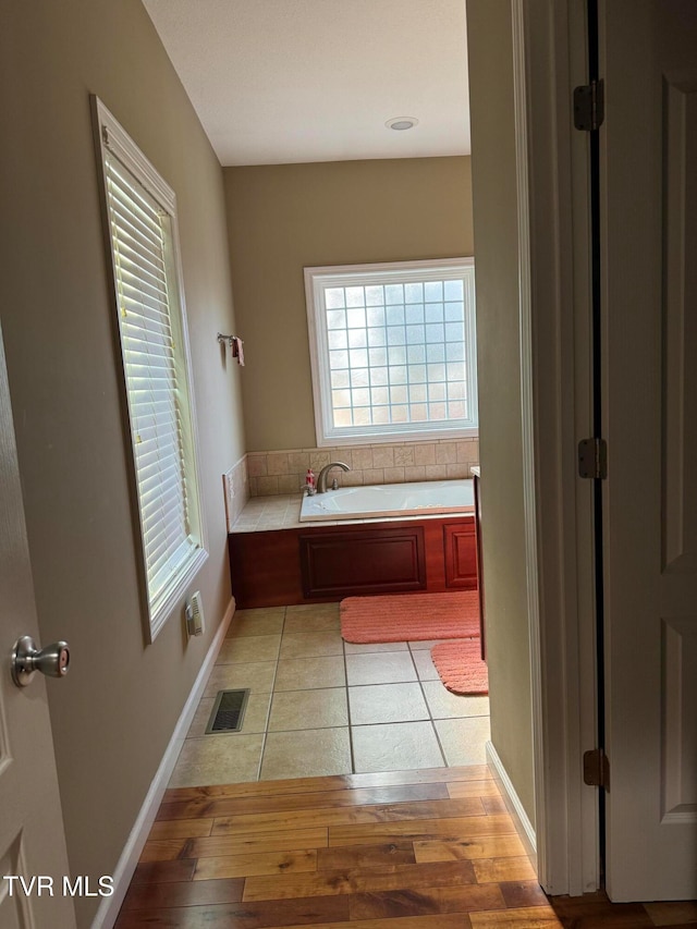 bathroom with hardwood / wood-style floors and a bath