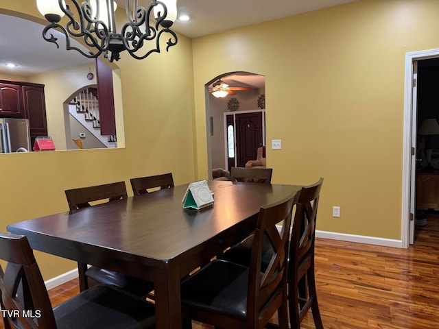 dining room with ceiling fan with notable chandelier and hardwood / wood-style flooring