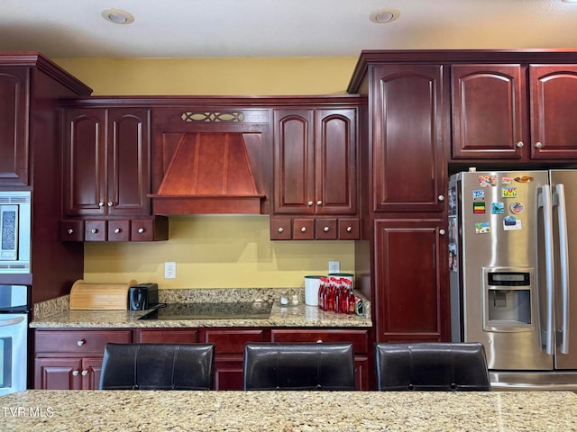 kitchen featuring light stone countertops, appliances with stainless steel finishes, and custom exhaust hood