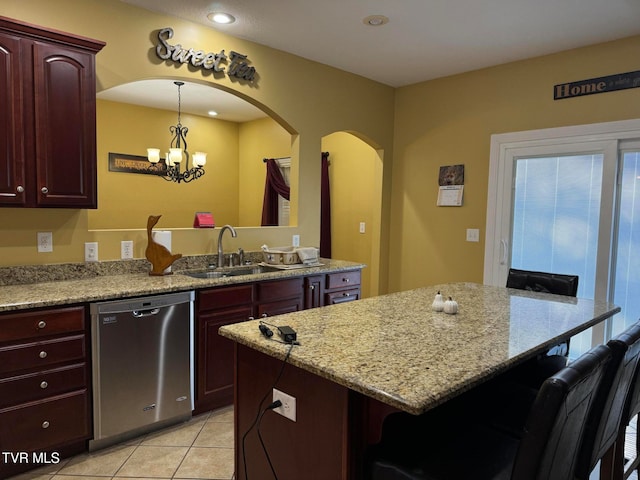 kitchen featuring light stone counters, stainless steel dishwasher, a chandelier, a kitchen bar, and light tile patterned floors