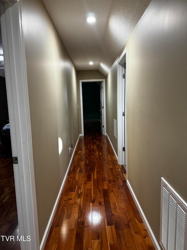 hallway with vaulted ceiling and dark hardwood / wood-style floors