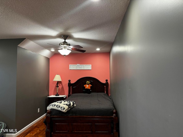 bedroom with a textured ceiling, hardwood / wood-style flooring, vaulted ceiling, and ceiling fan