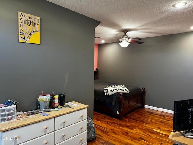 bedroom featuring dark hardwood / wood-style floors, ceiling fan, and a textured ceiling