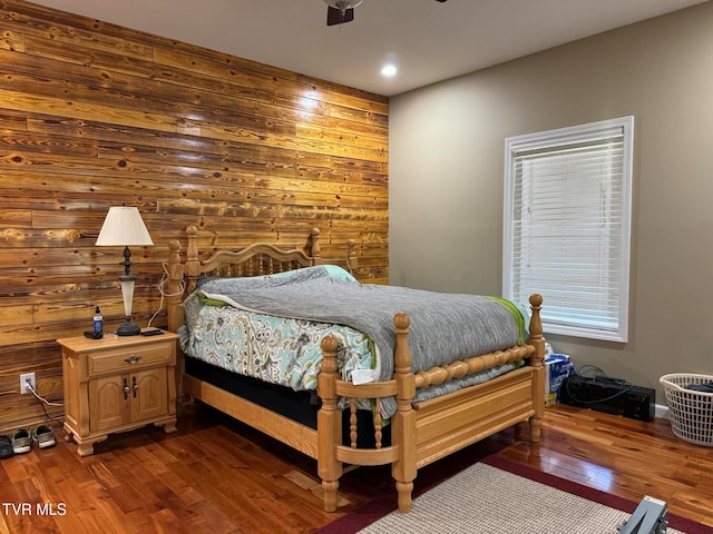 bedroom featuring wood walls, hardwood / wood-style floors, and ceiling fan