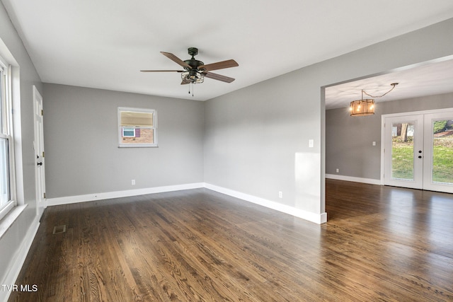 empty room with french doors, ceiling fan with notable chandelier, and dark hardwood / wood-style floors