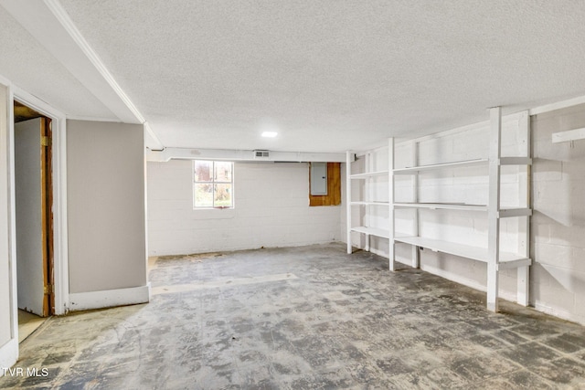 basement with a textured ceiling and electric panel