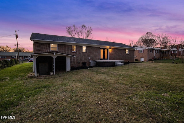 back house at dusk with central air condition unit and a yard