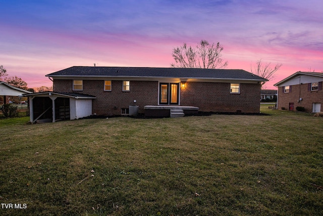 back house at dusk with a yard, central AC unit, and a storage shed