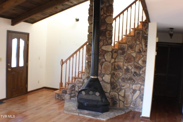 foyer with hardwood / wood-style floors, vaulted ceiling with beams, a wood stove, and wooden ceiling