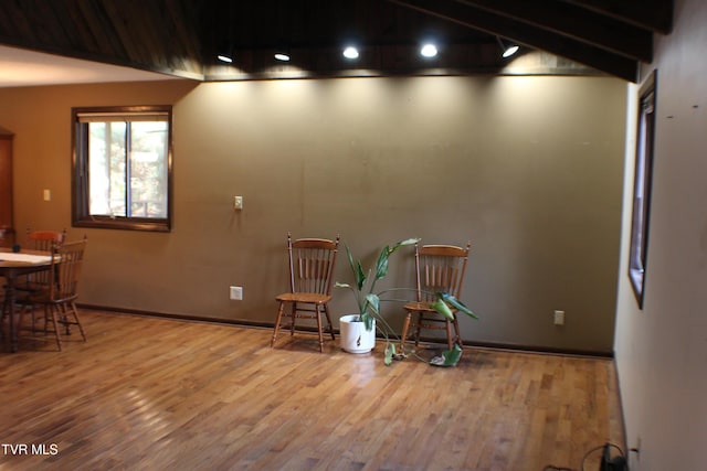 living area with beam ceiling and hardwood / wood-style flooring