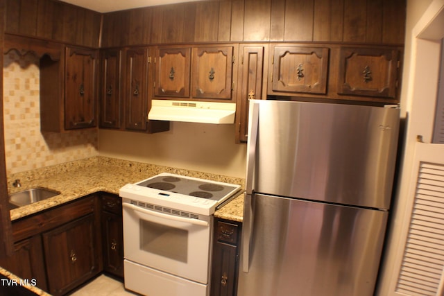 kitchen featuring stainless steel refrigerator, light stone countertops, sink, and white electric range