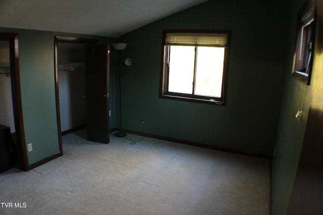 unfurnished bedroom with a closet, light colored carpet, and lofted ceiling