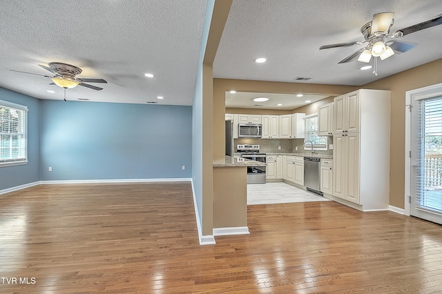 kitchen featuring white cabinets, a textured ceiling, light wood-type flooring, and stainless steel appliances