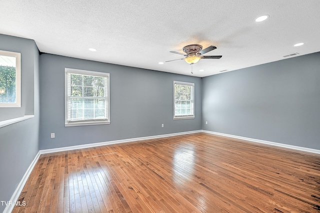 empty room with hardwood / wood-style floors, a textured ceiling, and a wealth of natural light