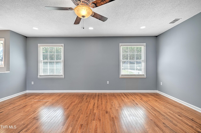 empty room with ceiling fan, a textured ceiling, and light wood-type flooring