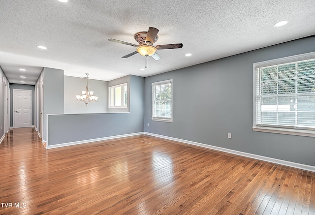 spare room with ceiling fan with notable chandelier, wood-type flooring, and a textured ceiling