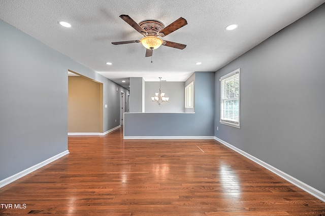 unfurnished room with ceiling fan with notable chandelier, dark wood-type flooring, and a textured ceiling