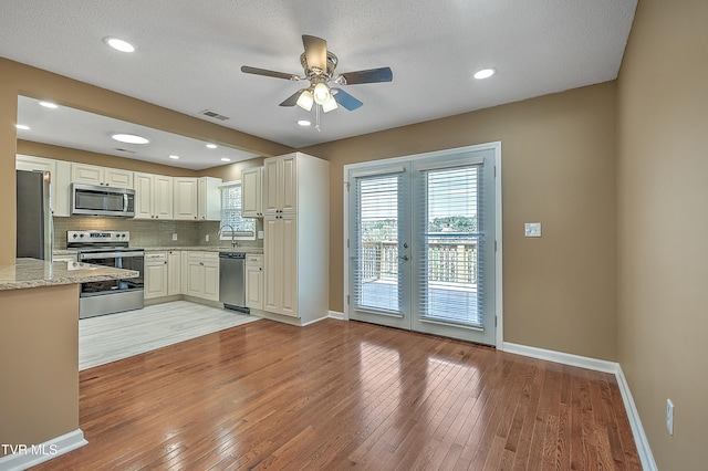 kitchen featuring appliances with stainless steel finishes, light wood-type flooring, a textured ceiling, and french doors