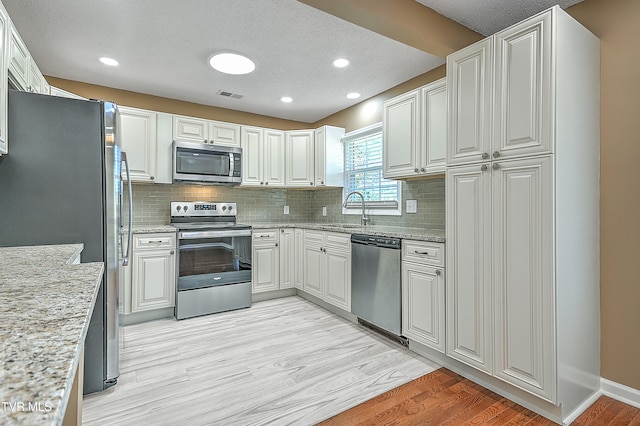 kitchen featuring white cabinetry, sink, appliances with stainless steel finishes, and light hardwood / wood-style flooring