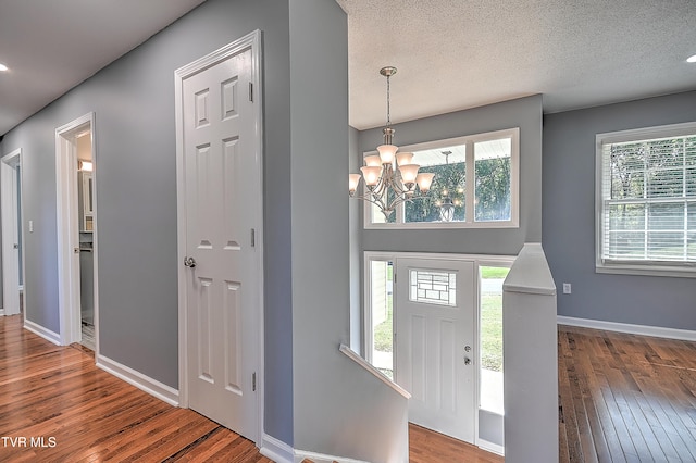 foyer entrance featuring hardwood / wood-style floors, a textured ceiling, and a notable chandelier