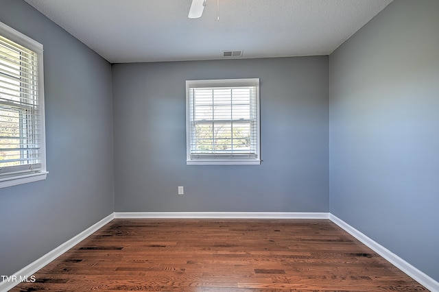 unfurnished room featuring a healthy amount of sunlight, dark hardwood / wood-style flooring, and a textured ceiling