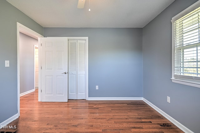 unfurnished bedroom with ceiling fan, dark hardwood / wood-style flooring, a textured ceiling, and a closet