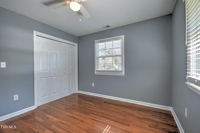 unfurnished bedroom featuring a textured ceiling, ceiling fan, dark wood-type flooring, and a closet