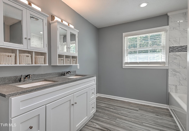 bathroom with hardwood / wood-style flooring, vanity, and shower / tub combination