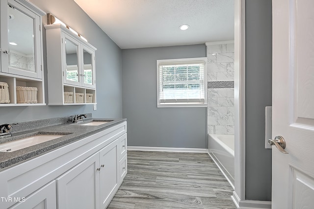 bathroom with tiled shower / bath, vanity, a textured ceiling, and hardwood / wood-style flooring