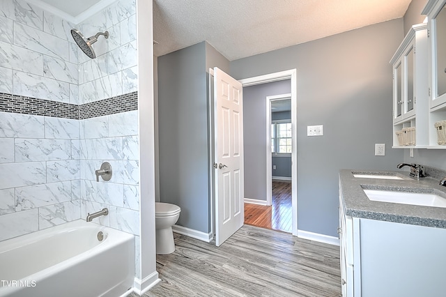 full bathroom featuring a textured ceiling, toilet, hardwood / wood-style flooring, vanity, and tiled shower / bath