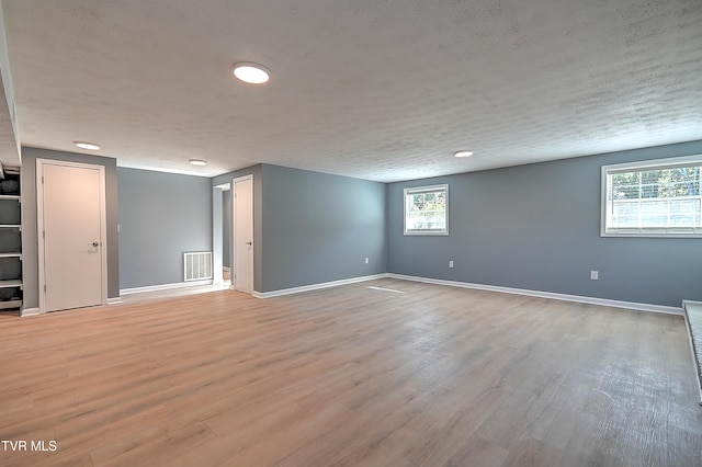 unfurnished room featuring a textured ceiling, light wood-type flooring, and plenty of natural light